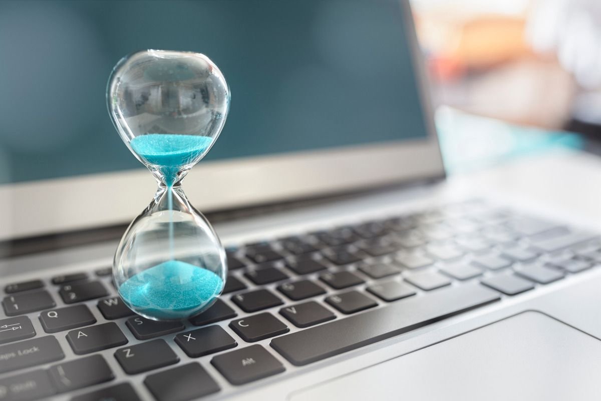 Ampulheta com areia azul sobre o teclado de um notebook